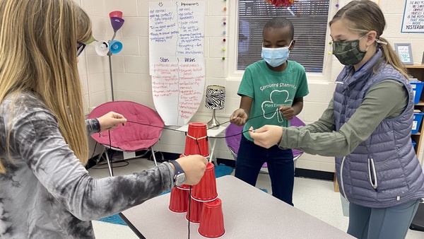 Middle School students work together to build a cup pyramid.